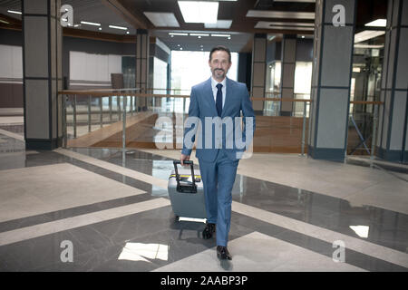 Fröhliche bärtigen Geschäftsmann eingabe Hotel während einer Geschäftsreise Stockfoto