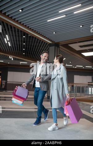 Liebevoller Ehemann Lächeln, während im Gespräch mit seiner Frau nach Wochenende einkaufen Stockfoto