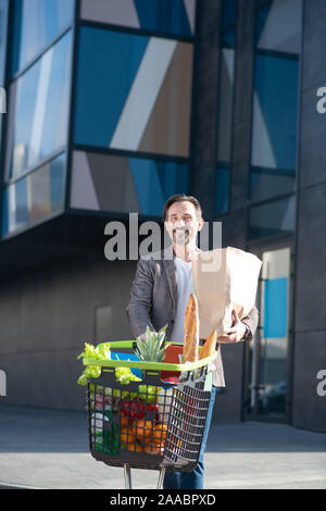 Bärtiges Lächeln, Geschäftsmann, Supermarkt nach dem Kauf von Lebensmitteln Stockfoto