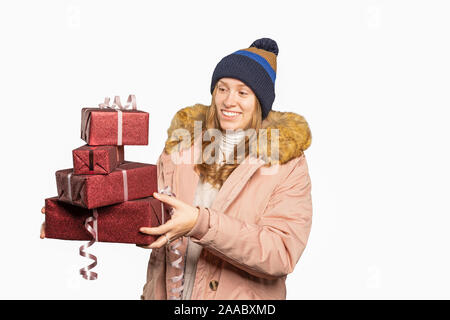 Junge Frau in Winterkleidung mit einem Stapel Weihnachtsgeschenke Stockfoto