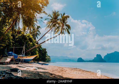 Banca Boot am Ufer unter Palmen. Tropische Insel, die malerische Landschaft. El-Nido, Palawan Stockfoto