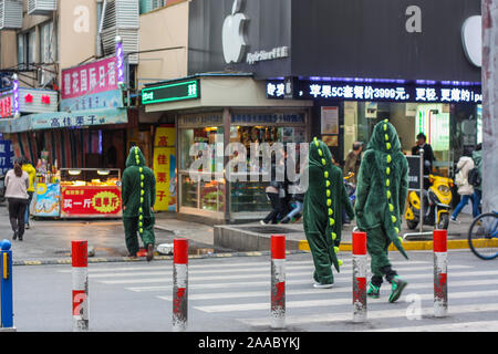 Nantong City/China - November 10, 2013: Drei jugendlich Leute in Krokodil outfit Verteilung business Broschüre Flyer im Geschäftsviertel der Stadt. Stockfoto