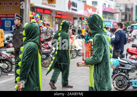 Nantong City/China - November 10, 2013: Drei Leute in Krokodil outfit Verteilung business Broschüre Flyer im Geschäftsviertel der Stadt. Moti Stockfoto