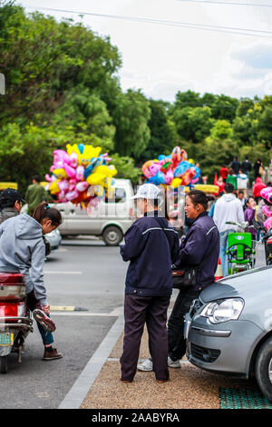 Nantong City/China - Oktober 3, 2011: Tag an einem Wochenende Familie Karneval. Parkwächtern in den Vordergrund der Unterhaltung mit der Dame auf dem Motorroller. Stockfoto