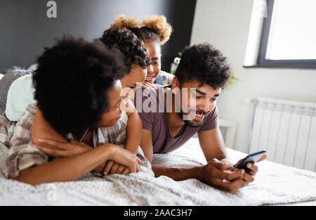 Eltern mit Kindern geniessen Sie Spiele spielen oder unterhaltsam mit mobilen Anwendungen auf dem Telefon zu Hause Stockfoto