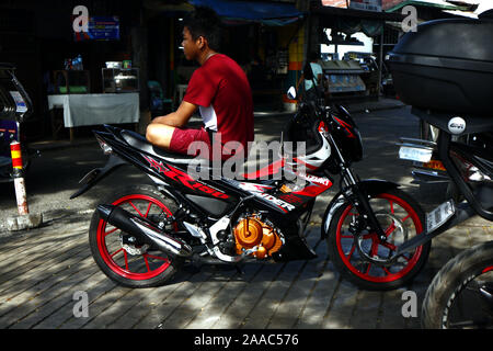 ANTIPOLO CITY, Philippinen - 20 November, 2019: Motorradfahrer ruht auf seinem Motorrad während an einem öffentlichen Parkplatz geparkt. Stockfoto