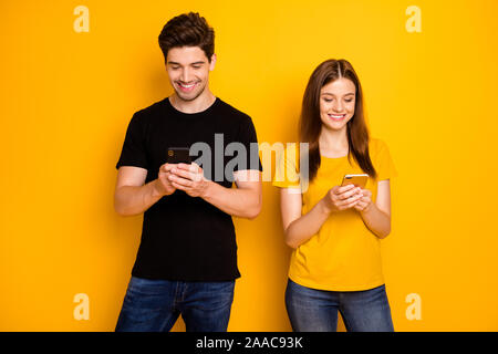 Foto von roten Haaren brunette charmante Süße nettes hübsches Paar in ihre Telefone mit schwarzen t-shirt Jeans Denim lächelnd toothily Stockfoto