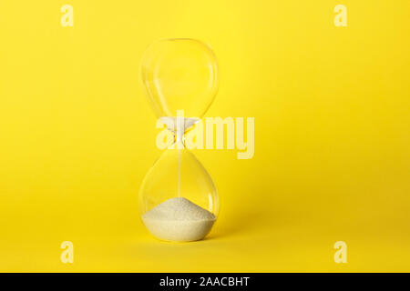 Die Zeit läuft. Eine Sanduhr mit Sand durch Fallen, auf ein leuchtend gelber Hintergrund mit Kopie Raum Stockfoto