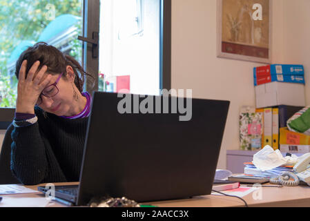 Betonte Frau bei der Arbeit in Büro vor dem Notebook. Burn-out-Syndrom Konzept Stockfoto