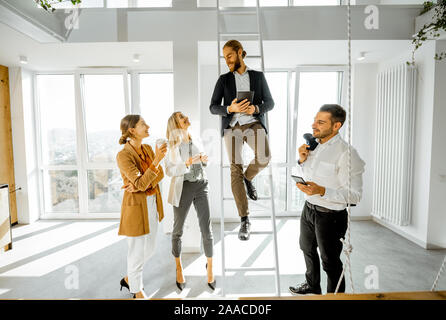 Eine Gruppe von jungen, kreativen Mitarbeitern in einige informelle Diskussion, während in der hellen Tagungsraum mit grossen Fenstern Stockfoto