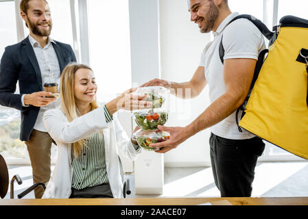 Kurier liefern gesunde Geschäftsessen mit thermal Bag für die Mitarbeiter, indem Sie ihnen Takeaway Salate im Büro Stockfoto