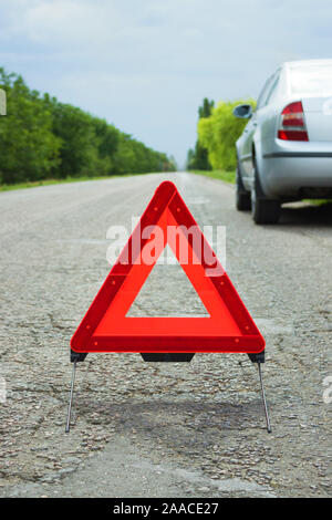 Auto mit Problemen und ein rotes Dreieck, um andere Verkehrsteilnehmer zu warnen. Stockfoto