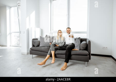 Junges Paar entspannen Sie sich auf der bequemen Couch, Fernsehen im hellen Wohnzimmer einer modernen Wohnung Stockfoto