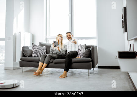 Junges Paar entspannen Sie sich auf der bequemen Couch, Fernsehen im hellen Wohnzimmer einer modernen Wohnung Stockfoto