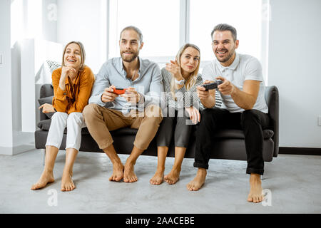 Gruppe von jungen Freunden Spaß beim Spielen von Videospielen auf der Couch zu Hause. Konzept von Freizeit und video Spiele zu Hause Stockfoto