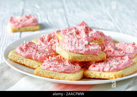 Köstlich süßen Shortbread Cookies mit Strawberry vanilla buttercream frosting auf einer weißen Platte auf einem Holztisch, Ansicht von oben, close-up Stockfoto