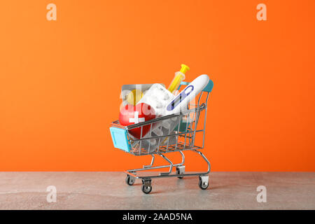 Mini Warenkorb mit medizinischen Versorgung auf orangem Hintergrund, in der Nähe Stockfoto
