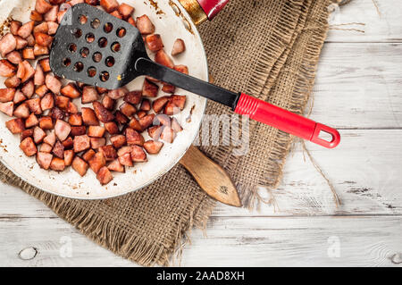 Gebratene Würstchen in Scheiben in einem Würfel auf einer Pfanne auf einem hölzernen Hintergrund. Stockfoto