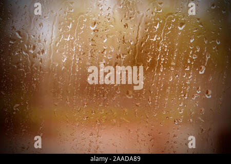Regen fällt auf Glas Fenster in orange Ton. Stockfoto