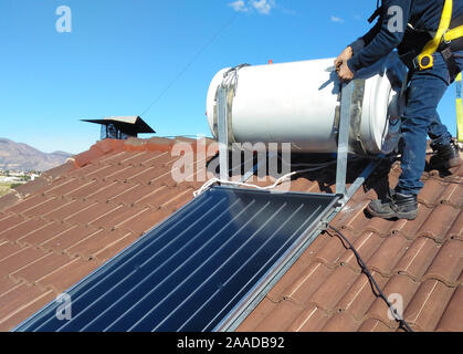 Mann, die Installation von alternativen Energien Photovoltaik-Solarzellen auf Dach Stockfoto