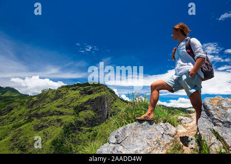 Frau genießen Sie einen wunderschönen Blick auf den wolkenverhangenen Himmel und Hügel von der Oberseite der kleinen Adams Peak in der Nähe von Ella, Sri Lanka. Tracking im Freien touristische Abenteuer. Stockfoto