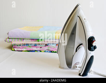 Moderne Bügeleisen und Stapel von gebügelte Bettwäsche. Hausarbeiten. Stockfoto