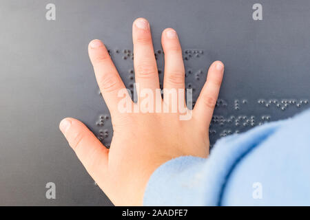 Ein blindes Kind Hand auf einen Text in Blindenschrift geschrieben. Stockfoto