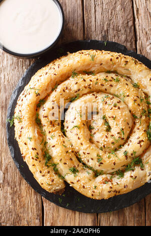 Traditionelle Balkan pie Borek (burek) mit Feta mit Joghurt in der Nähe serviert - auf den Tisch. Vertikal oben Ansicht von oben Stockfoto