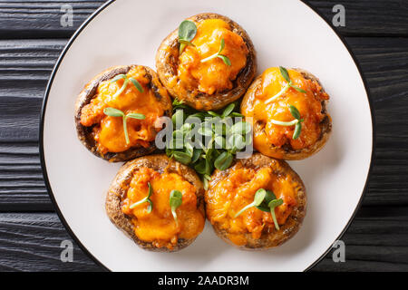 Pilze Champignons gefüllt mit Hackfleisch und Cheddar Käse close-up auf einem Teller auf den Tisch. horizontal oben Ansicht von oben Stockfoto