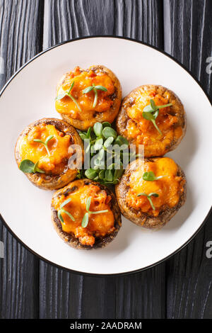 Gebackene Portobello Pilze mit Hackfleisch und Cheddar Käse close-up auf einem Teller auf den Tisch. Vertikal oben Ansicht von oben Stockfoto