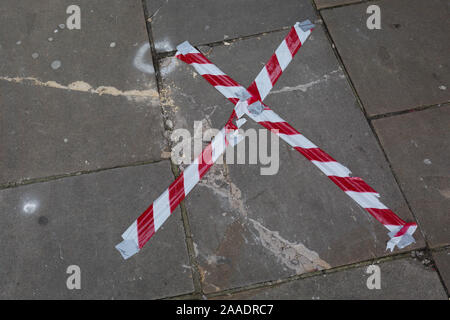 Gefahr Band wird über einen gebrochenen Pflastersteine Platte auf einem clerkenwell Straße im Stadtteil Islington gestreckt, am 20. November 2019 in London, England. Stockfoto