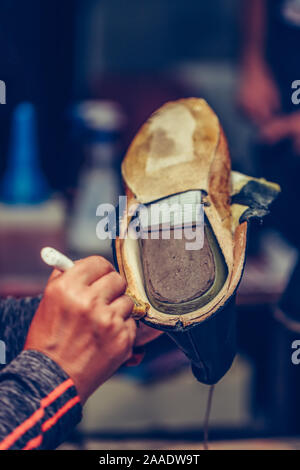 Die Hände eines erfahrenen Arbeiter in den handgefertigten Schuhindustrie, alleinige kleben Aufgaben, Leim auf die Teile der Schuh. Selektiver Fokus Stockfoto