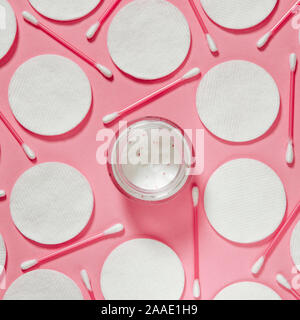 Hygiene Produkte: Weiße runde Wattepads und Kunststoff Sticks für die Reinigung der Ohren liegen auf einem rosa Hintergrund nächste Creme zu Gesicht Stockfoto