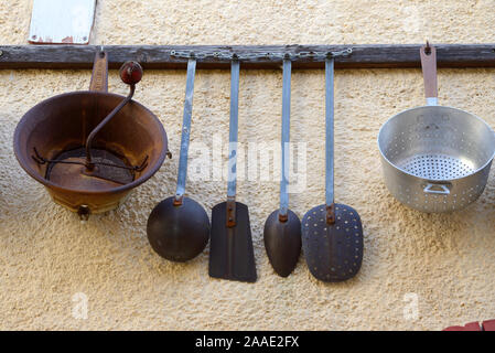 Vintage oder antiken Sammlung alter Küchengeräte hängen an der Wand Rack einschließlich Pfannen, Trockenleger & Spatel Stockfoto