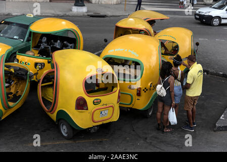 Eine kleine Flotte gelber Cocotaxi auf einem Parkplatz in Havannas Altstadt ( Habana Vieja) in Kuba. Das Cocotaxi, ein vertrauter Anblick auf der Straße, zuerst Stockfoto