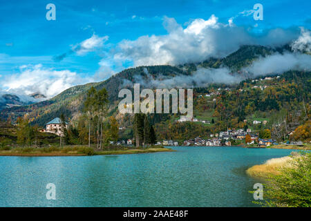 Panoramablick auf den Lago di Alleghe See in den italienischen Dolomiten auf hellen Herbst Tag mit Reflexionen des Dorfes im Wasser Stockfoto