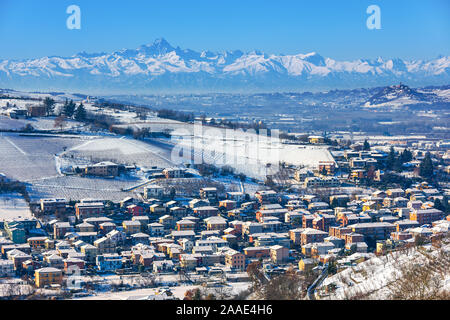 Blick auf die kleine Stadt Alba, Hügel und Berge im Hintergrund im Schnee in Piemont, Norditalien abgedeckt. Stockfoto