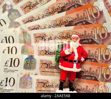 Ein Weihnachtsmann Figur stehend vor einige neue zehn Pfund Noten. England Großbritannien Stockfoto