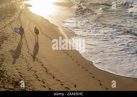 Fußabdrücke auf dem Sandstrand von Playa La Pared Strand bei Sonnenuntergang mit zwei Surfer wandern, Fuerteventura, Spanien Stockfoto