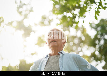 Senior asiatischer Mann mit weißem Haar wandern draußen im Park Stockfoto