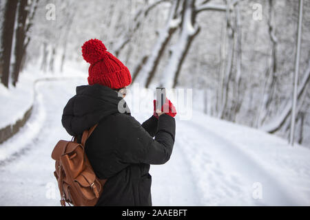 Frau im Winter Outfit zu Fuß durch die verschneiten Park Road Stockfoto