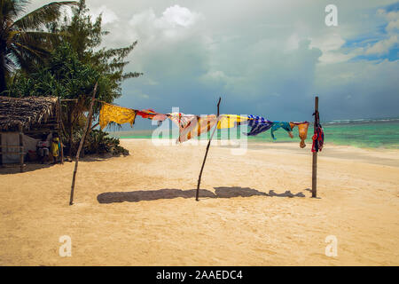 Diani, Mombasa, Kenia, Afrika Oktober 13, 2019 hell Afrikanische Kleidung stehen auf der Wäscheleine getrocknet und entwickelt in den Wind an einem Strand in der Nähe des Ozeans o Stockfoto