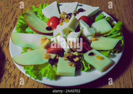 Ansicht von oben. Käseplatte mit verschiedenen Sorten Käse mit Thymian Walnüsse und Tomaten. Käseplatten serviert mit Gequetschten auf einem Holzbrett. Stockfoto