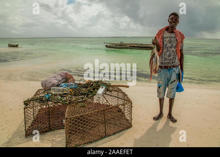 Diani, Mombasa, Kenia, Afrika Oktober 13, 2019 afrikanische Mann mit einem Notebook und einem frischen Fang von Fischen steht am Ufer der Eichenholz an einem sonnigen Tag. Stockfoto