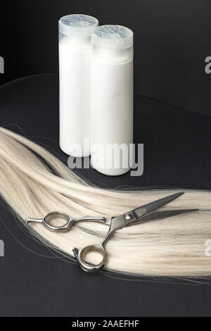 Shampoo für coloriertes Haar. Mockup Flasche Shampoo für blondes. Weiße Flaschen kosmetisches Produkt, professionellen Friseur Schere und blonde Haare auf Stockfoto