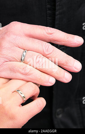 Trauringe auf seine Hände. Ein älteres Paar heiratete. Glückliche Familie. Familie im Freien Stockfoto