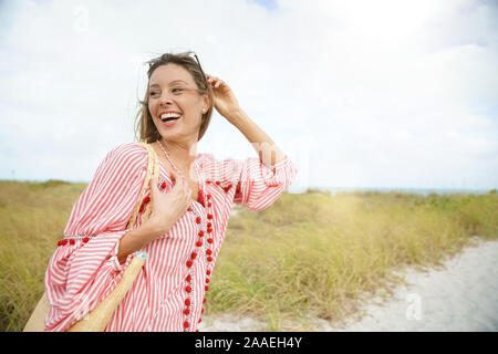 Attraktive junge Frau im Urlaub am Strand lächelnd Stockfoto
