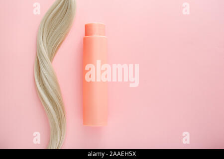 Shampoo für coloriertes Haar. Mockup Flasche Shampoo für blondes. Rosa Flasche kosmetisches Produkt und blondes Haar auf Rosa farbigen Hintergrund. Platz für Stockfoto