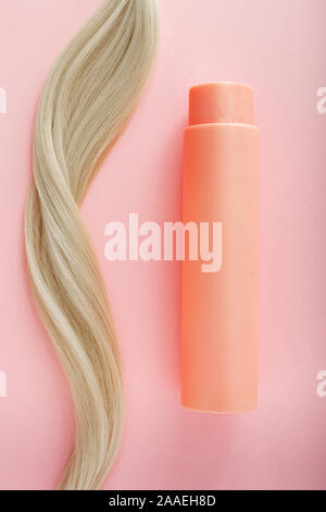 Shampoo für coloriertes Haar. Mockup Flasche Shampoo für blondes. Rosa Flasche kosmetisches Produkt und blondes Haar auf Rosa farbigen Hintergrund. Platz für Stockfoto