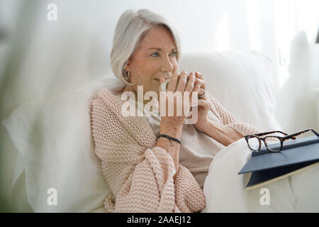 Schöne ältere Frau im Bett lesen Stockfoto